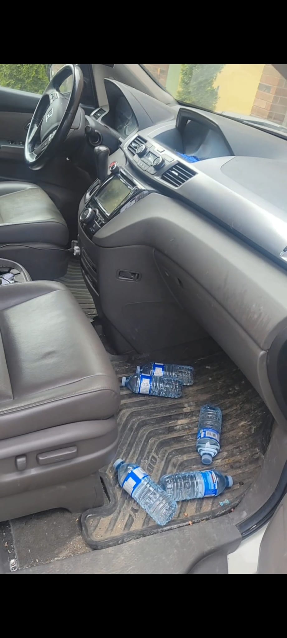 Before photo of the 2012 Honda Odyssey interior showing bottles, dirt, and neglected floor mats